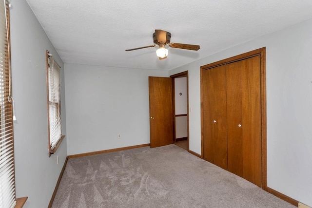 unfurnished bedroom featuring carpet, a closet, a ceiling fan, baseboards, and a textured ceiling