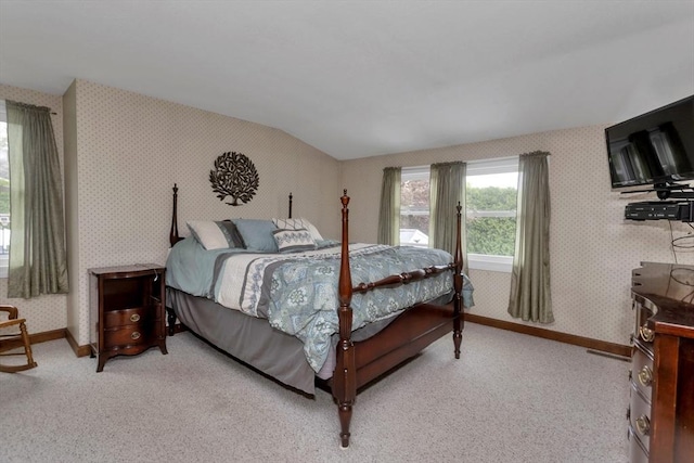 bedroom with wallpapered walls, light colored carpet, baseboards, and vaulted ceiling