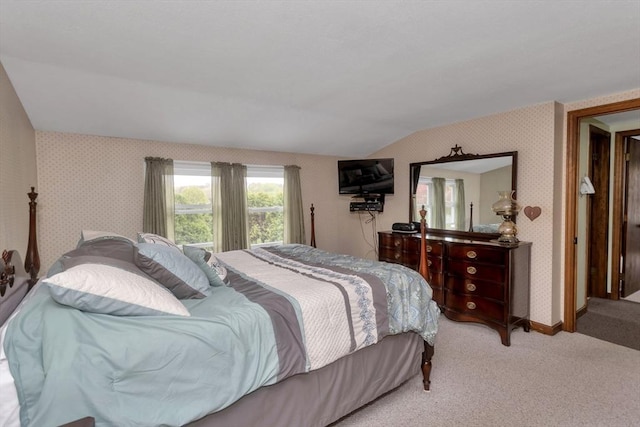 bedroom with light colored carpet, vaulted ceiling, baseboards, and wallpapered walls