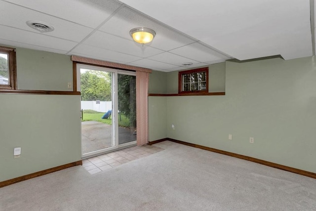 carpeted spare room featuring baseboards, healthy amount of natural light, and a paneled ceiling