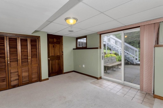 unfurnished bedroom with access to outside, light carpet, baseboards, a closet, and a paneled ceiling