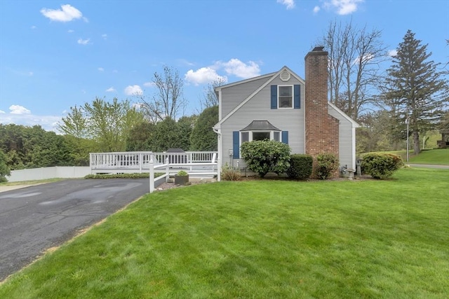 view of side of home with a chimney and a yard