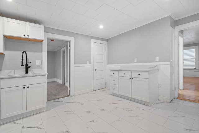 kitchen with crown molding, white cabinetry, and sink