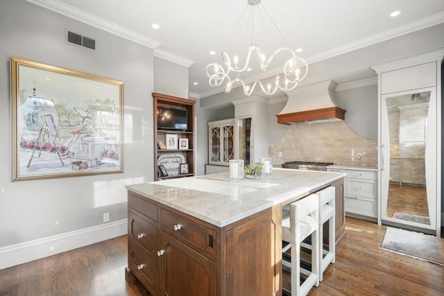 kitchen featuring custom range hood, backsplash, white cabinets, dark wood-type flooring, and a kitchen island