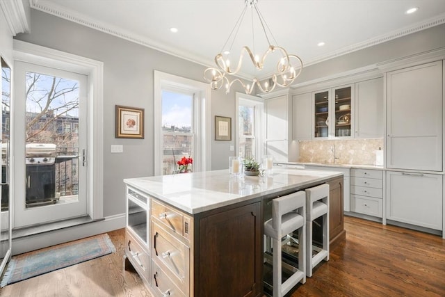 kitchen with pendant lighting, dark wood-type flooring, white cabinetry, tasteful backsplash, and a kitchen island