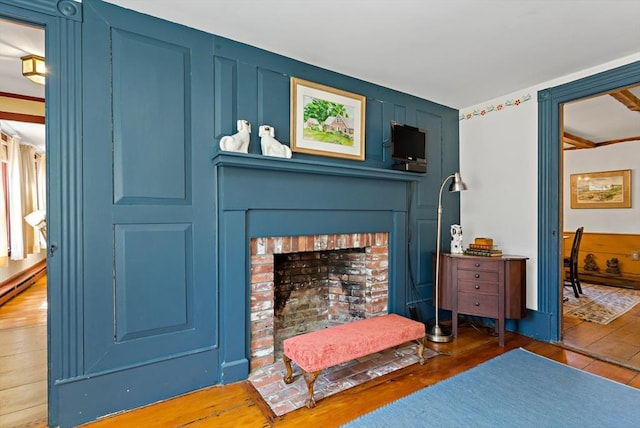 interior space with a fireplace, a decorative wall, and wood finished floors