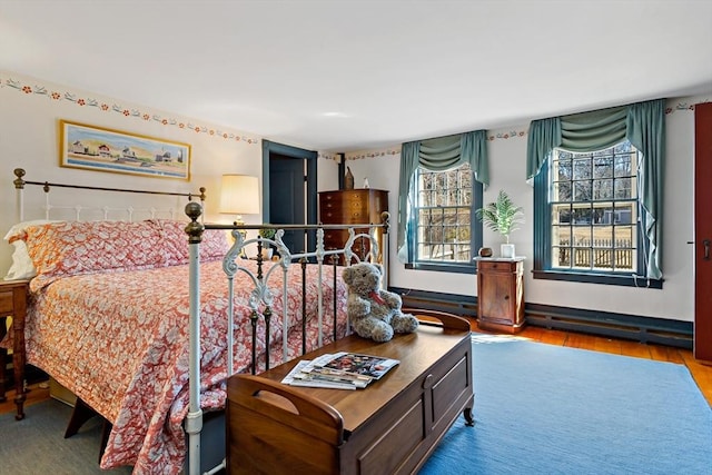 bedroom with baseboard heating and wood finished floors