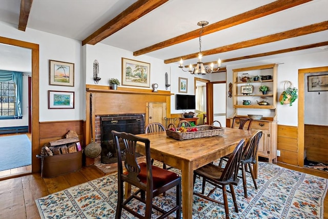 dining room with beam ceiling, wainscoting, a fireplace, and hardwood / wood-style flooring