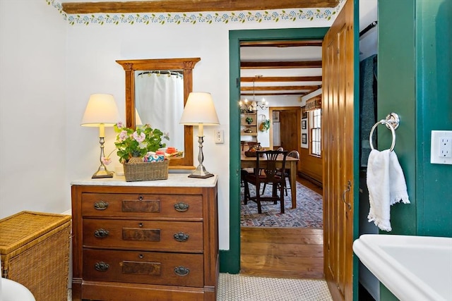 hallway featuring beamed ceiling and an inviting chandelier