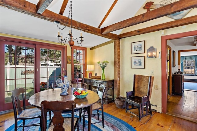 dining area featuring lofted ceiling with beams, hardwood / wood-style floors, and a notable chandelier