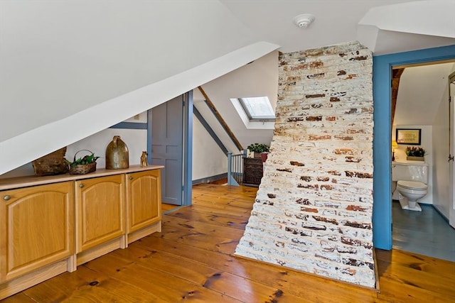 bonus room featuring vaulted ceiling with skylight and hardwood / wood-style floors