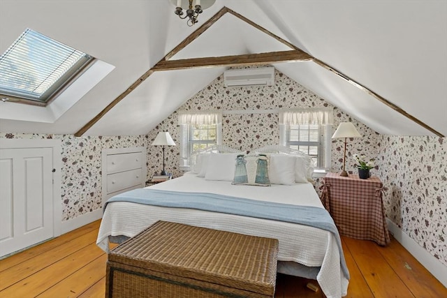 bedroom featuring vaulted ceiling with skylight, multiple windows, a wall mounted air conditioner, and wallpapered walls