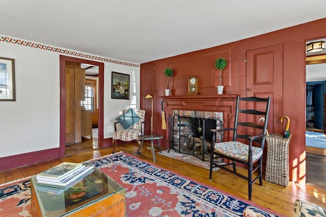 sitting room with hardwood / wood-style flooring, a fireplace, and baseboards