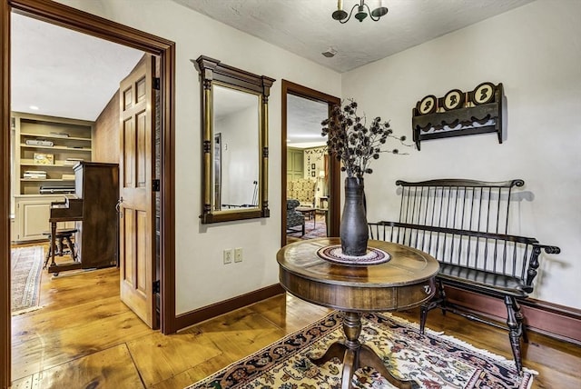 corridor featuring built in features, baseboards, and light wood-style floors