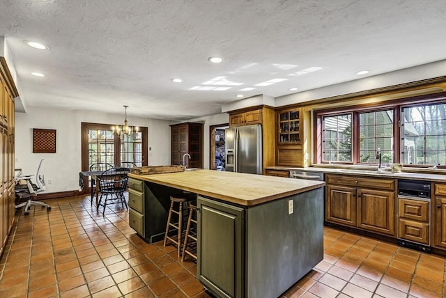 kitchen with a healthy amount of sunlight, a center island with sink, appliances with stainless steel finishes, and butcher block countertops