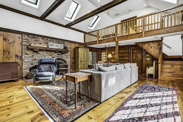 living room with wooden walls, built in features, stairs, a skylight, and wood-type flooring