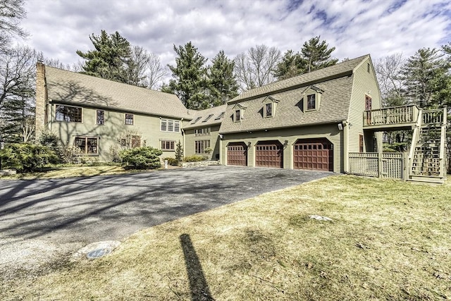 view of front of home featuring a gambrel roof, driveway, roof with shingles, a garage, and stairs