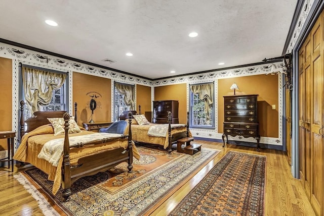 bedroom featuring visible vents, light wood-style flooring, recessed lighting, crown molding, and baseboards