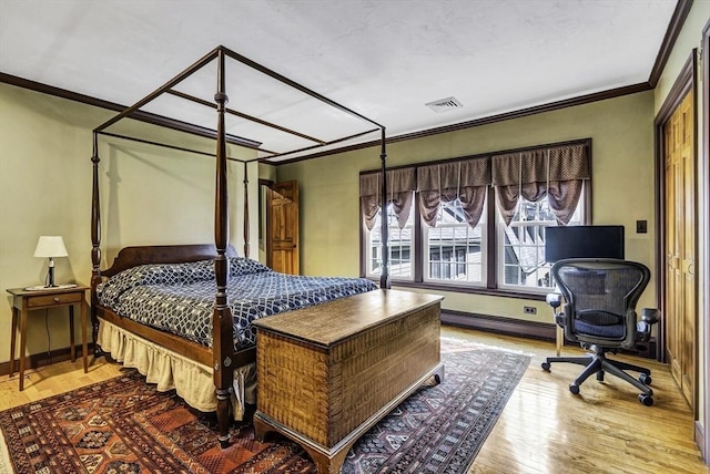 bedroom featuring visible vents, wood finished floors, baseboards, and ornamental molding