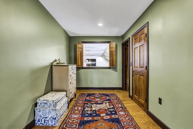 hall with light wood-style flooring and baseboards