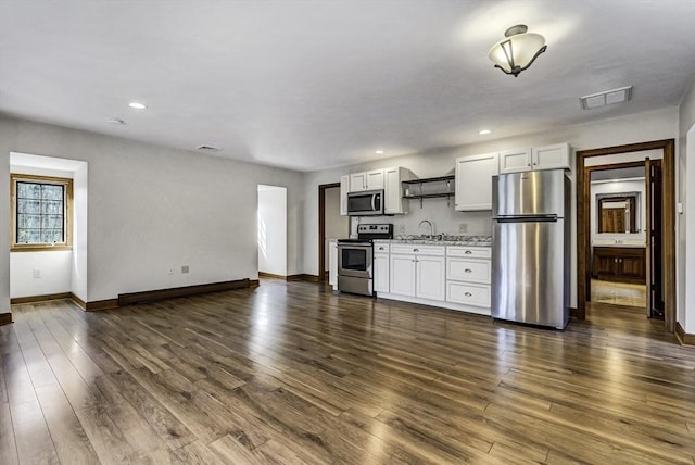 kitchen with visible vents, a sink, white cabinets, stainless steel appliances, and dark wood-style flooring