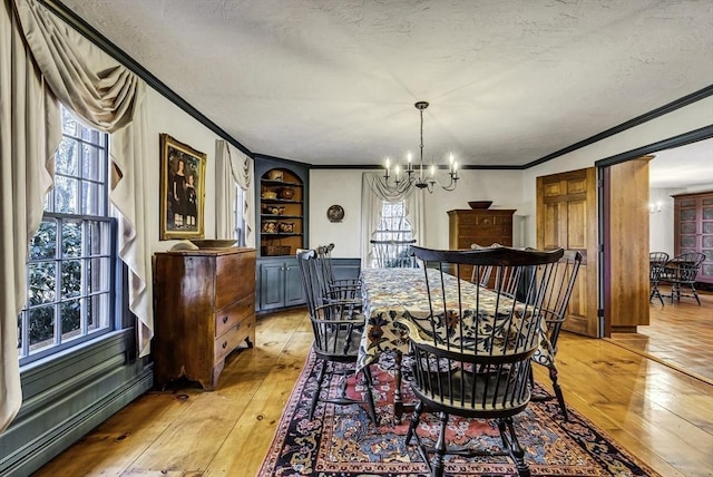 dining room featuring a chandelier, light wood-type flooring, a baseboard heating unit, and ornamental molding