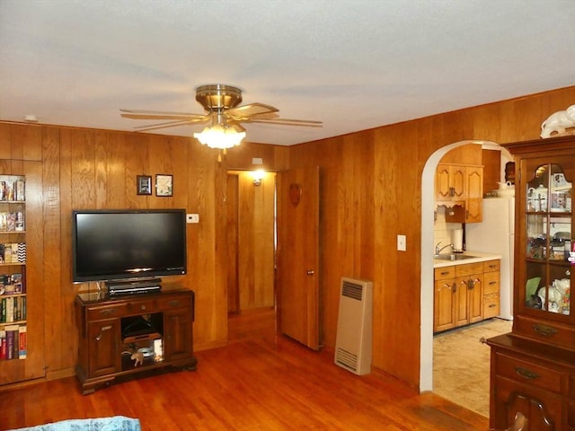 living room featuring wooden walls, sink, ceiling fan, and hardwood / wood-style floors