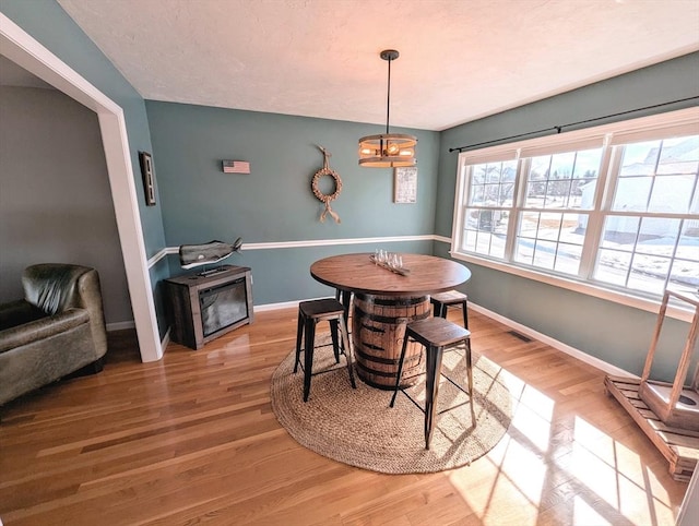 dining space with visible vents, baseboards, a chandelier, and wood finished floors