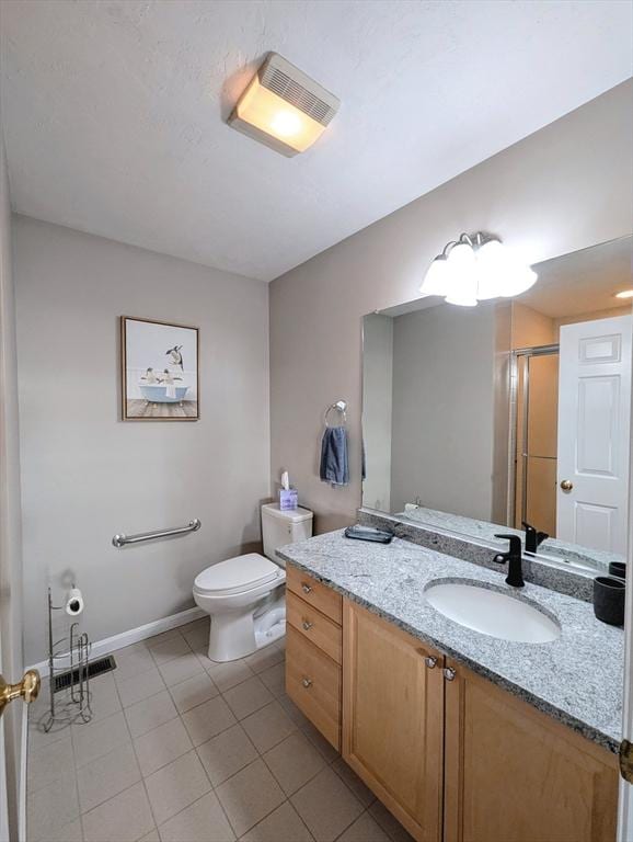 bathroom with a stall shower, baseboards, toilet, tile patterned flooring, and vanity