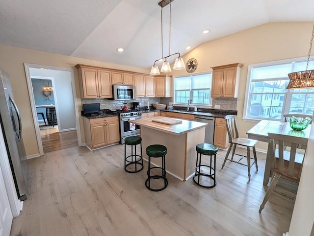 kitchen with appliances with stainless steel finishes, vaulted ceiling, backsplash, and light brown cabinetry