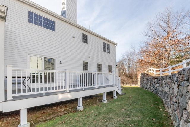 rear view of house with a wooden deck, a chimney, fence, and a yard