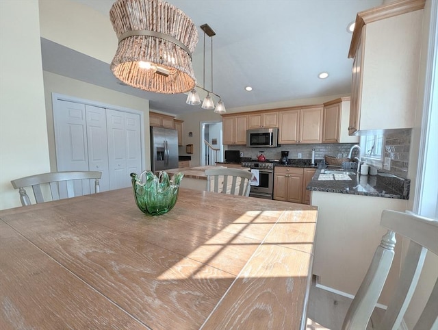 kitchen with decorative backsplash, dark countertops, a center island, stainless steel appliances, and light brown cabinetry