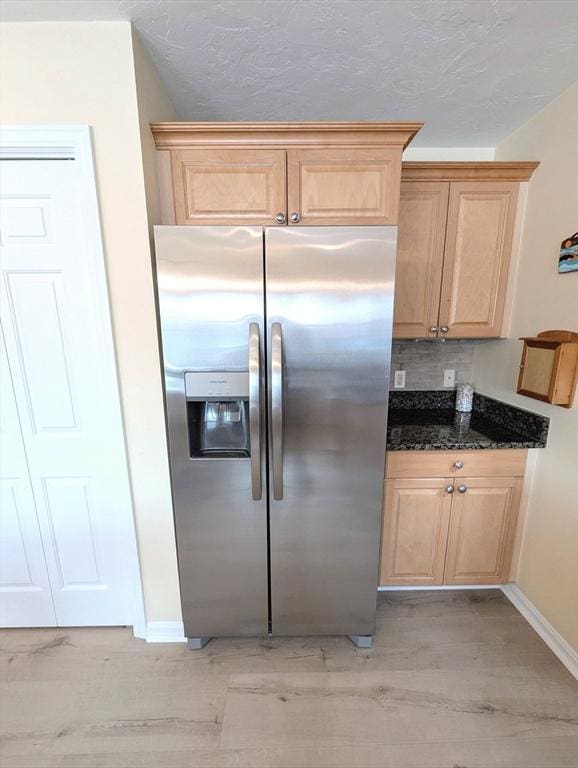 kitchen with a textured ceiling, stainless steel refrigerator with ice dispenser, and light brown cabinets