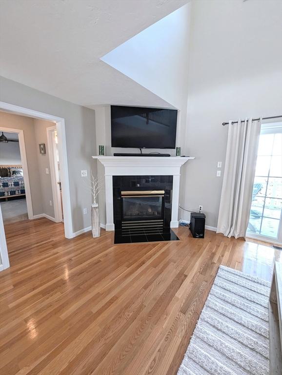 living room with baseboards, a tiled fireplace, and wood finished floors