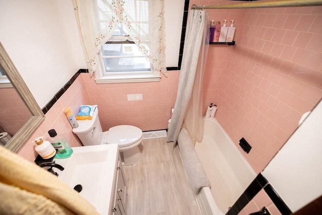 full bathroom with hardwood / wood-style floors, shower / bathtub combination with curtain, vanity, tile walls, and toilet