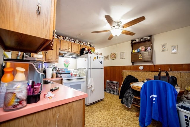 kitchen with ceiling fan, white appliances, and wooden walls