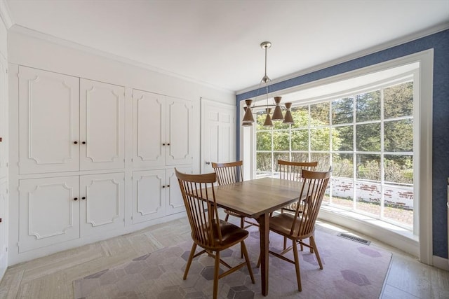 dining room with healthy amount of natural light, crown molding, and a chandelier