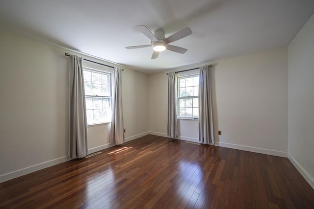 unfurnished room with dark wood-type flooring, a ceiling fan, and baseboards