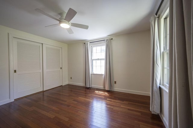 unfurnished bedroom featuring dark wood-type flooring, a closet, baseboards, and a ceiling fan