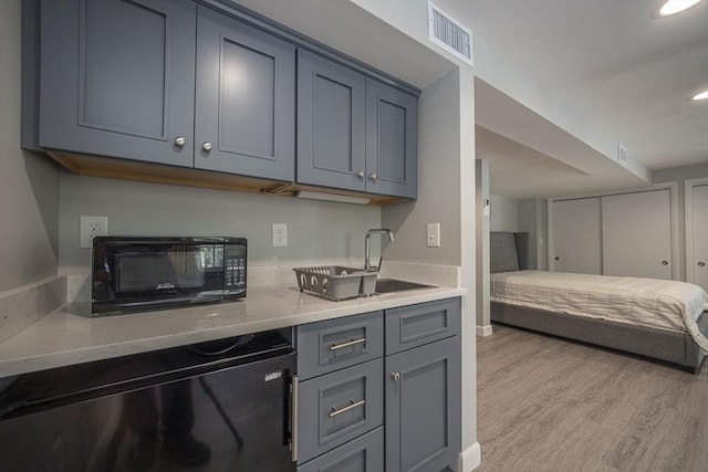 kitchen featuring gray cabinets, light wood-style floors, a sink, fridge, and recessed lighting