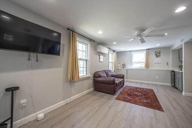 living area with light wood-style flooring, a ceiling fan, a wall mounted air conditioner, baseboards, and recessed lighting