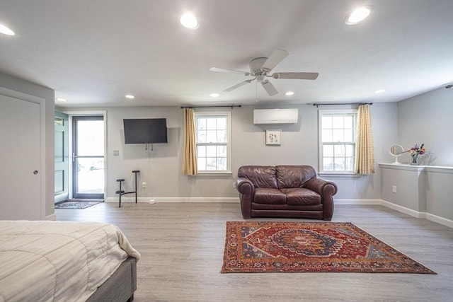 bedroom with a wall mounted air conditioner, recessed lighting, baseboards, multiple windows, and wood finished floors