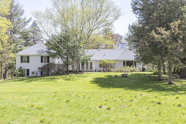rear view of property featuring a chimney and a lawn