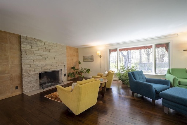 living room featuring dark wood finished floors and a stone fireplace