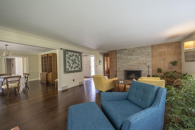 living room with a fireplace, dark wood finished floors, baseboards, a chandelier, and ornamental molding