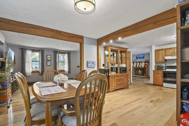 dining room featuring light hardwood / wood-style flooring, beam ceiling, and a fireplace