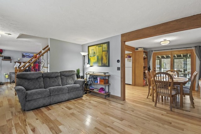 living room with light hardwood / wood-style floors, radiator, and beam ceiling