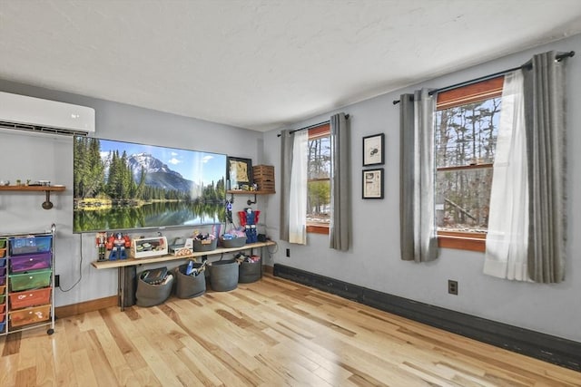 rec room with light hardwood / wood-style floors and a wall unit AC