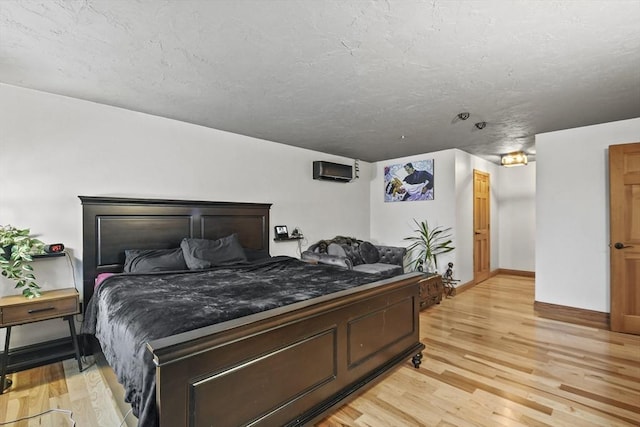 bedroom featuring light hardwood / wood-style floors and a wall unit AC