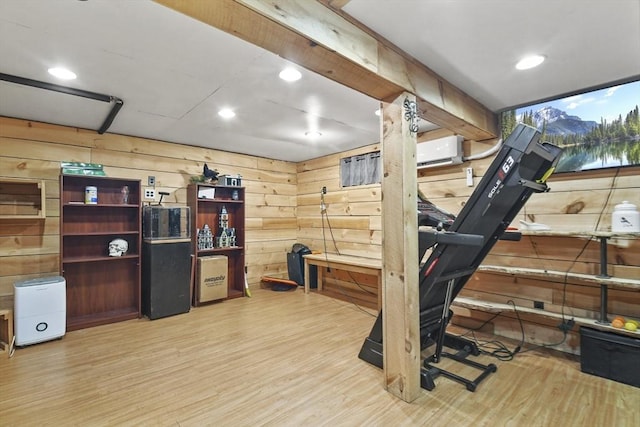 exercise room featuring light hardwood / wood-style flooring, wood walls, and a wall mounted air conditioner